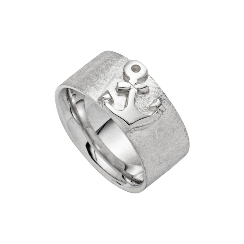 Ring „Fetter Anker“ (R5399) aus 925er Sterling-Silber, markant gearbeitet mit einer Breite von ca. 8 mm. Das kraftvolle Design verbindet maritime Symbolik mit einer klaren, ausdrucksstarken Form. Im Mittelpunkt steht ein polierter Anker, der sich glänzend vom gebürsteten, matten Untergrund abhebt. Dieser bewusste Kontrast verleiht dem Ring Tiefe und unterstreicht die hochwertige Verarbeitung. Der Anker als klassisches Symbol steht für Halt, Sicherheit und die Verbundenheit zum Meer. Die Innenseite des Rings ist glatt gearbeitet und sorgt für ein angenehmes Tragegefühl im Alltag. Die Rhodinierung verleiht dem Schmuckstück einen besonders langlebigen Glanz und schützt das Silber zusätzlich vor dem Anlaufen. Ein stilvolles Statement für alle, die maritime Designs und klare Formen schätzen.